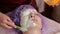 An experienced cosmetologist prepares a healthy mask for the client. She gets up and touches the face with a brush. A