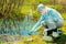 experienced ecologist on the shore of a forest lake takes water