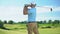 Experienced golf player hitting ball in draw position at course, back view