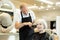 Experienced hairdresser using round hairbrush to style hair to elderly woman