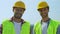 Experienced male builders in helmets and uniform smiling on camera, good service