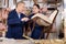 Experienced male restorer teaches young female employee how to remove upholstery of vintage chair for restoration in