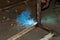 An experienced man performs work with a welding machine by fastening metal parts in an industrial workshop