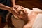 Experienced massage therapist stimulating acupoint on woman face