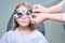 Experienced optometrist conducting subjective refraction test on little girl