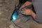 An experienced person performs work with a welding machine, fixing metal parts, removing blue smoke and yellow sparks and