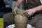 Experienced potter makes a large vase on a potter`s wheel. clay product. hands of a potter. reportage shooting