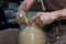 Experienced potter makes a large vase on a potter`s wheel. twisting a narrow neck. clay product