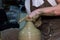 Experienced potter makes a large vase on a potter`s wheel. twisting a narrow neck. clay product