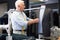 Experienced tailor tries on a new jacket on a mannequin in workshop