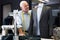 Experienced tailor tries on a new jacket on a mannequin in workshop
