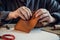 An experienced tanner sews a clasp for a leather product with stitches