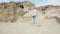 Experienced tourist explores old ancient city, slowly rises up slope of white stone, young woman in a white flying shirt