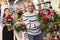 Experienced woman florist helping male client to choose flowers in shop