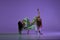 Experimental dance. Two young girl in motion, action isolated over purple background. Emotions, love, style, youth