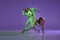 Experimental dance. Two young girl in motion, action  over purple background. Emotions, love, style, youth