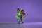 Experimental dance. Two young girl in motion, action  over purple background. Emotions, love, style, youth