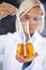 Experimentation is the heart of discovery. a lab technician holding up a beaker of yellow fluid.