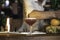 An expert bartender preparing a cocktail in a night club bar counter, view of the drink on the counter and a cheerful barman in