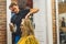 Expert male stylist styling blond hair of his young adult female client. Hairdresser interior. Blurred background, copy