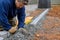 An expert paver worker lays stones on the ground for the paving of a pathway by the master.