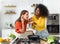 Explore the heartwarming connection between two women engaged in a lively discussion while standing in a well-lit kitchen,