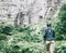 Explorer woman walking to waterfalls on high cliff.