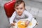 Exploring new tastes. A cute little baby sitting in a highchair eating solid food.