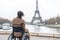 Exploring Paris as a wheelchair user. Back of disabled african american woman looking on Eiffel tower. Generative AI