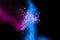 Explosion of pink blue colored powder isolated on black background.Blue pink dust splash