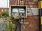 Exposed and tangled electrical wiring in an outdoor utility box on red brick wall