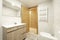 Exposed white brick bathroom with wood vanity, Venetian cabinet