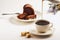 Exposition of chocolate cake with cup a coffee, coffee grinder on background. Black background.