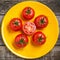 Exposition of fresh organic tomato, healthy food on yellow plate and wooden background.