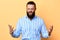 Expresive bearded man expresses negative emotion on a yellow background.