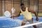 Expressive african american playing paddle ball on closed court