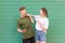 Expressive amusing couple listening to music in headphones on a green background,young man and the girl sing and watch each other.