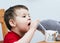 expressive boy drinking orange juice through a plastic straw