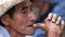 Expressive face of an old man, he plays with his hands while he rests in the street in the market of Xilitla village.