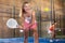 Expressive girl hitting two handed backhand during paddle tennis match