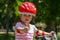 Expressive little girl with colorful red safety helmet riding a bicycle