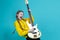 Expressive Positive Caucasian Teenager Guitar Player With Yellow Bass Guitar Posing In Fashionable Yellow Hoody Jacket With