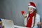 Expressive Positive Smiling Caucasian Girl Wearing Santa Hat Using Laptop for Online Video Virtual Chat While Holding And