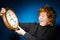 Expressive red-haired teenage boy showing time on big clock