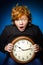 Expressive red-haired teenage boy showing time on big clock