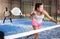 Expressive young sportswoman playing paddle tennis on indoor court