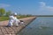 Exquisite fishing. Fisherman in white suit catch fish by spinning rod at trout area lake