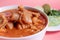 Exquisite Mexican Menudo on a white plate accompanied by a dish with condiments on the back