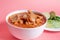 Exquisite Mexican Menudo on a white plate accompanied by a dish with condiments on the back