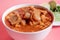 Exquisite Mexican Menudo on a white plate accompanied by a dish with condiments on the back